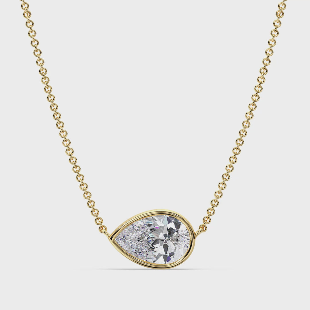 Close-up video showcasing a stunning 2 Carat Pear-Cut Lab-Grown Diamond Bezel-Set Solitaire Pendant Necklace in 18K Yellow Gold. The video highlights the brilliant sparkle of the IGI-Certified diamond, the elegant teardrop shape, and the sleek bezel setting. The vibrant yellow gold chain and pendant frame the diamond beautifully, creating a timeless and luxurious look.
