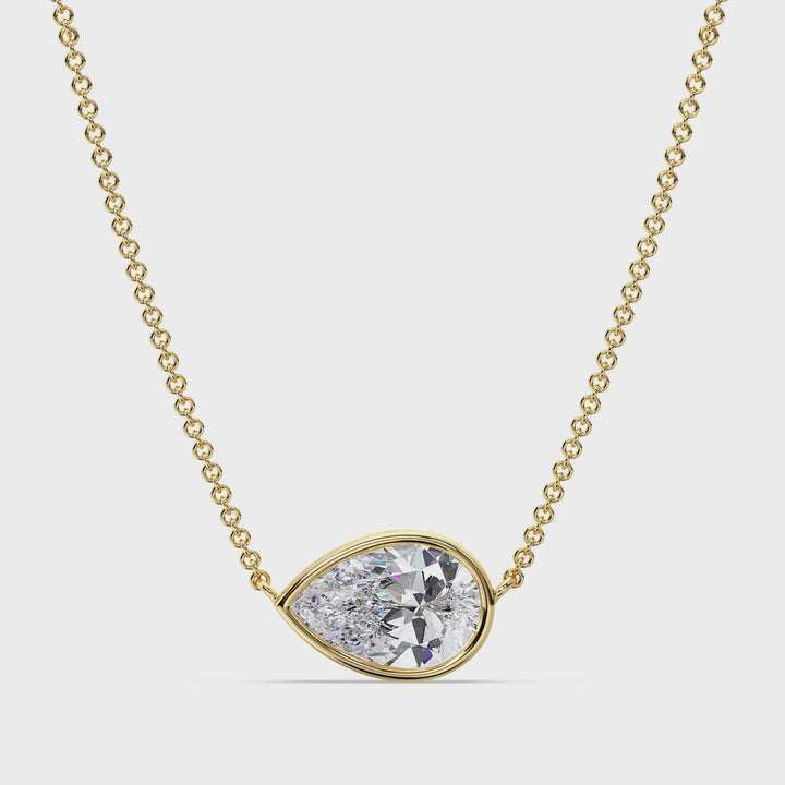 Close-up video showcasing a stunning 2 Carat Pear-Cut Lab-Grown Diamond Bezel-Set Solitaire Pendant Necklace in 18K Yellow Gold. The video highlights the brilliant sparkle of the IGI-Certified diamond, the elegant teardrop shape, and the sleek bezel setting. The vibrant yellow gold chain and pendant frame the diamond beautifully, creating a timeless and luxurious look.