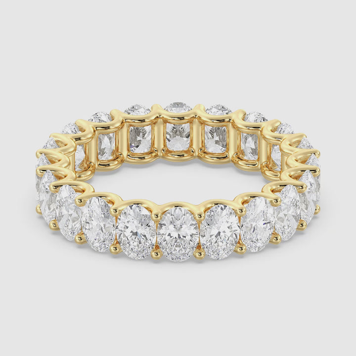 A close-up video showcasing the Elegant Oval Lab-Grown Diamond Scallop Eternity Band in 18K Yellow Gold. The video highlights the brilliance of the 20 oval-shaped diamonds set in a shared prong design, with a delicate scalloped side profile for added elegance. The band is rotated to display the diamonds' sparkle from every angle, emphasizing the luxurious craftsmanship and radiant yellow gold finish