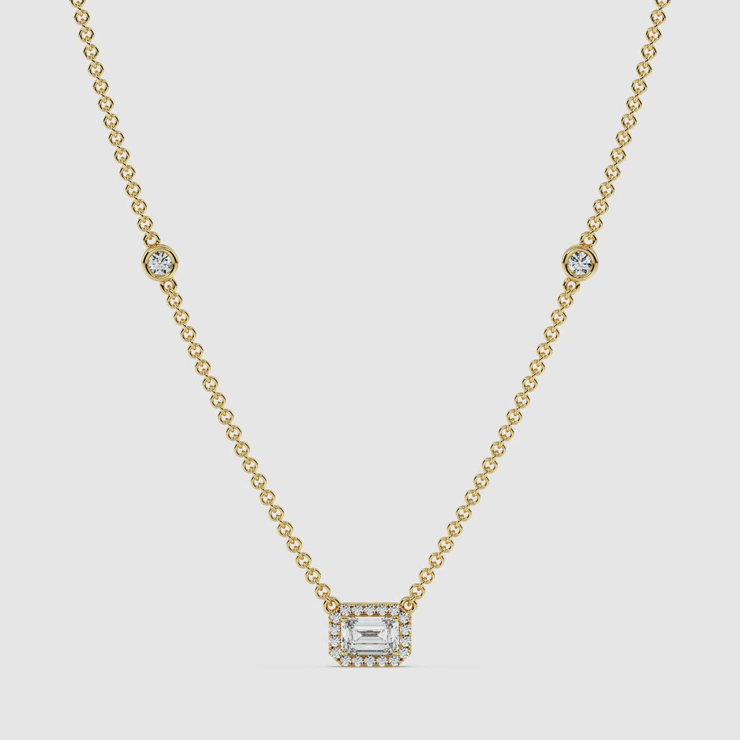video showcasing the Elegant Emerald-Cut Lab-Grown Diamond Station Necklace in 18K Yellow Gold. The necklace features a 1.00-carat emerald-cut diamond in a bezel setting, surrounded by a halo of round diamonds, with additional stationed diamonds along the chain, exuding brilliance and luxury