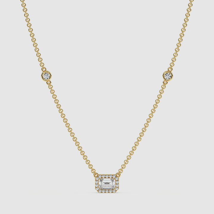 video showcasing the Elegant Emerald-Cut Lab-Grown Diamond Station Necklace in 18K Yellow Gold. The necklace features a 1.00-carat emerald-cut diamond in a bezel setting, surrounded by a halo of round diamonds, with additional stationed diamonds along the chain, exuding brilliance and luxury