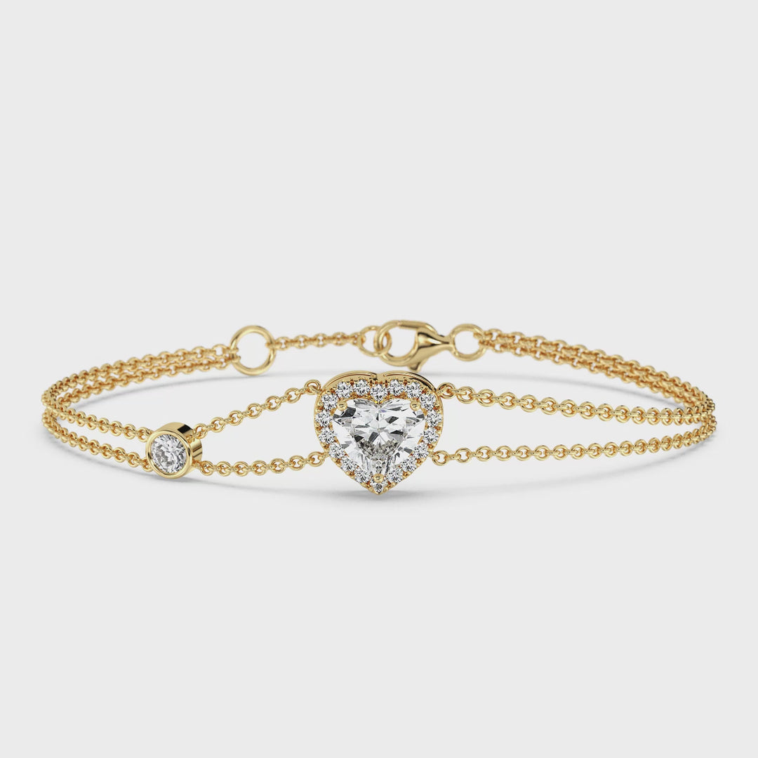 Close-up video of a double-chain bracelet in 18K yellow gold featuring a dazzling 1ct heart-cut lab-grown diamond in a halo setting. The bracelet sparkles with 19 round EF/VS lab-grown diamonds, accentuating the central stone. The warm yellow gold tone enhances the bracelet's elegance and sophistication as it gracefully moves under the light.