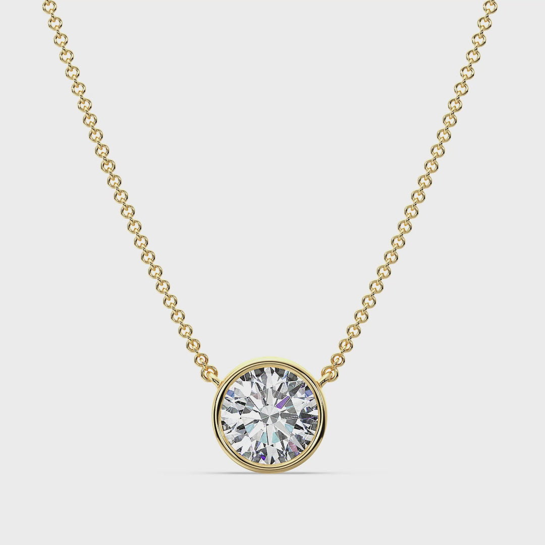 Close-up video of a stunning 2 Carat Bezel-Set Round Lab-Grown Diamond Solitaire Pendant Necklace in Yellow Gold. The IGI-certified diamond sparkles brilliantly in a sleek bezel setting, showcasing its radiant cut and colorless clarity. The pendant, crafted in luxurious 18K yellow gold, hangs gracefully on a matching chain, highlighting its timeless elegance and contemporary design. Perfect for weddings, special occasions, or everyday sophistication