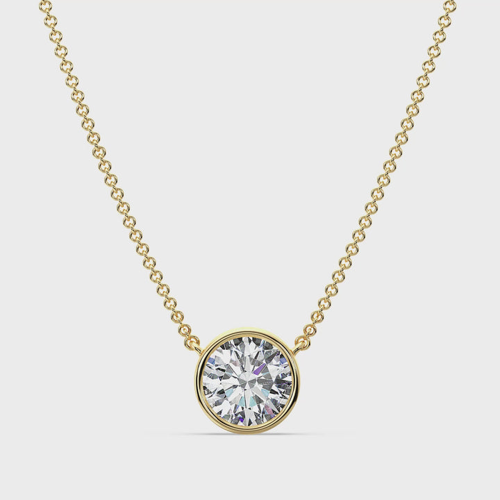 Close-up video of a stunning 2 Carat Bezel-Set Round Lab-Grown Diamond Solitaire Pendant Necklace in Yellow Gold. The IGI-certified diamond sparkles brilliantly in a sleek bezel setting, showcasing its radiant cut and colorless clarity. The pendant, crafted in luxurious 18K yellow gold, hangs gracefully on a matching chain, highlighting its timeless elegance and contemporary design. Perfect for weddings, special occasions, or everyday sophistication
