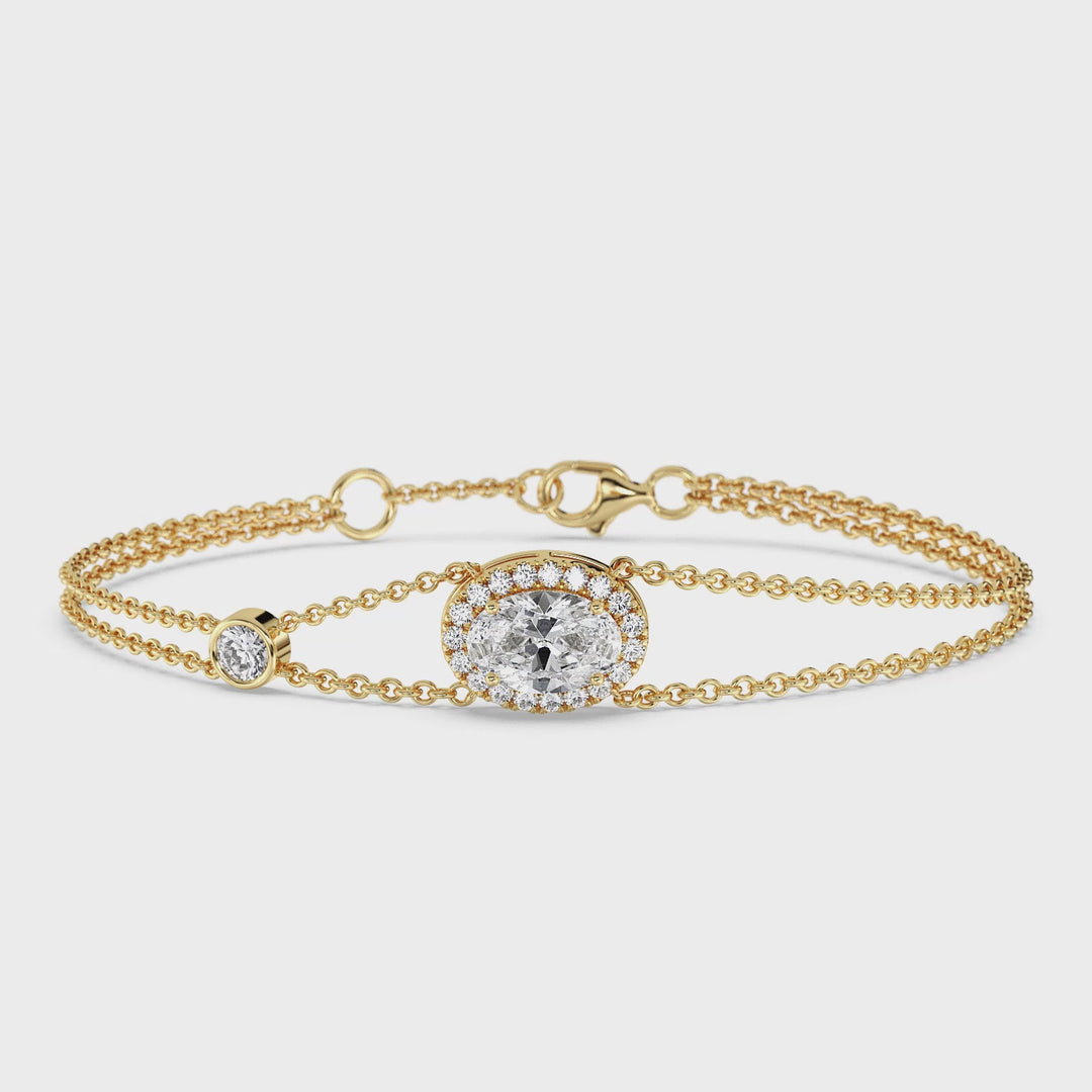Close-up video of a Double Chain 18K Yellow Gold Bracelet featuring a 1ct Oval-Cut Lab-Grown Diamond in a halo setting, surrounded by 20 sparkling Round-Cut EF/VS Lab-Grown Diamonds. The bracelet's warm yellow gold finish complements the brilliance of the diamonds, showcasing its luxurious and elegant design.