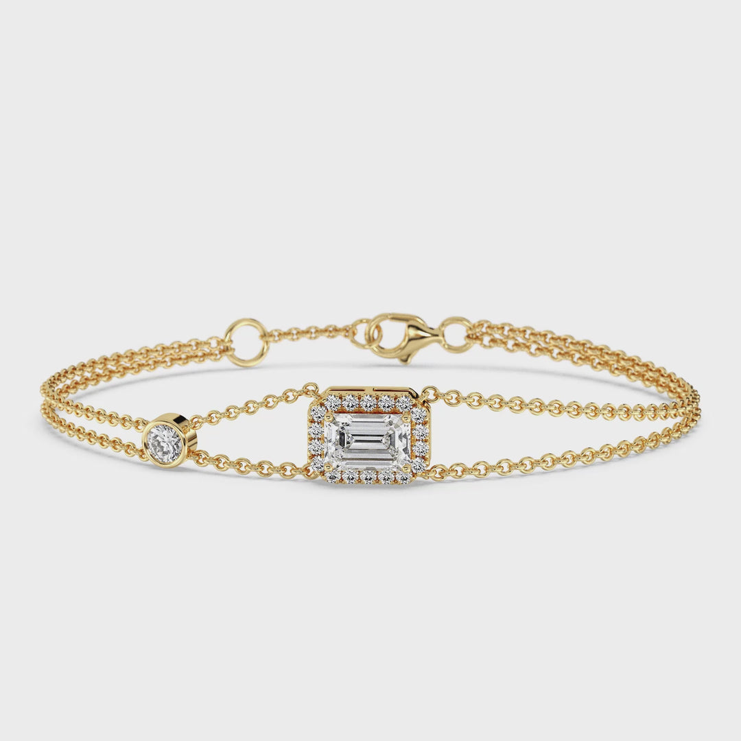 Close-up video of an elegant double-chain bracelet in 18K yellow gold, featuring a 1ct emerald-cut lab-grown diamond at its center surrounded by a halo of 19 round EF/VS lab-grown diamonds, showcasing the stunning sparkle and craftsmanship of the design.